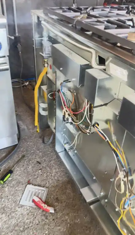 Back of a stainless pro-style gas range with wiring and gas line exposed
